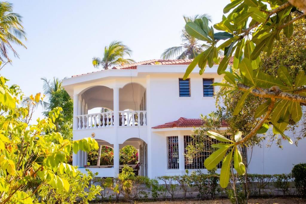 Casa blanca con balcón y árboles en Sand and Shells Beach House- 4 Bedroom with a pool, en Mombasa