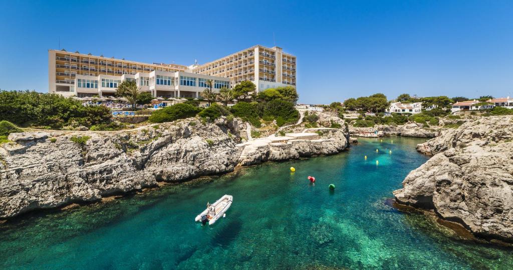 um barco em um corpo de água ao lado de algumas rochas em Globales Almirante Farragut em Cala en Blanes