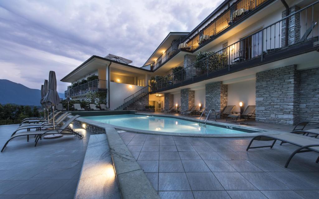 a house with a swimming pool in front of a building at Hotel La Perla in Tremezzo