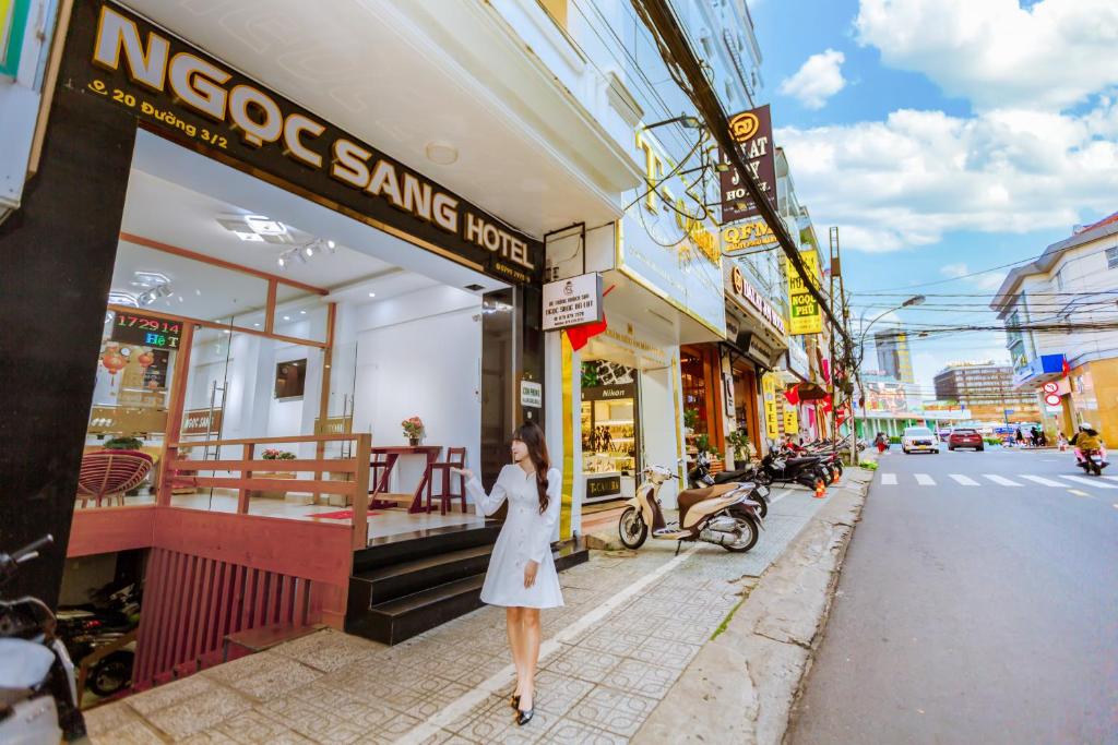 Une femme en robe blanche marchant dans une rue de la ville dans l'établissement Ngọc Sang 1 Hotel, à Đà Lạt