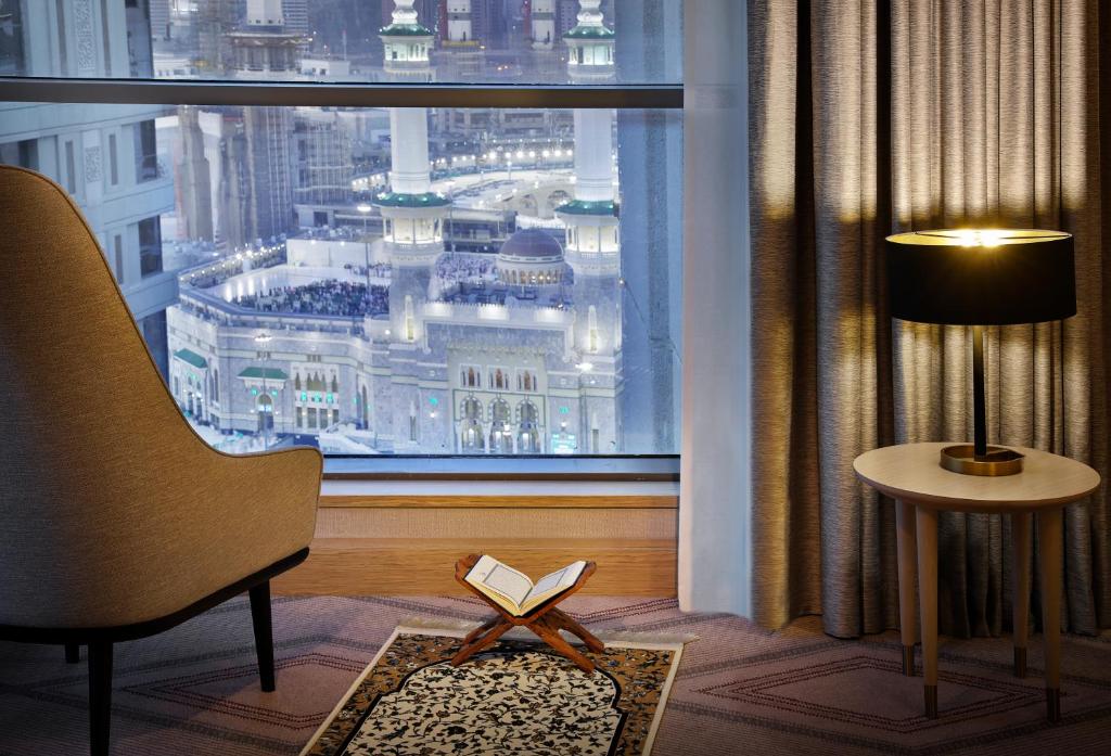 um quarto com uma janela com um livro e uma cadeira em Jumeirah Jabal Omar Makkah em Meca