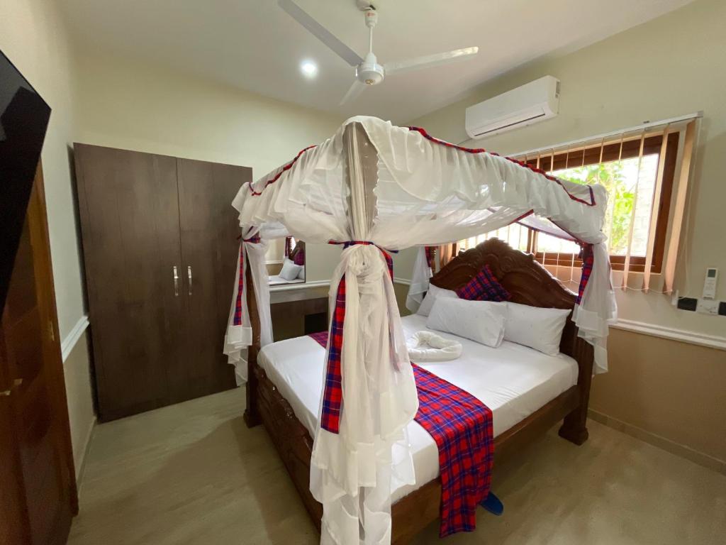 a bedroom with a bed with a canopy at Maasai Koroga in Mombasa