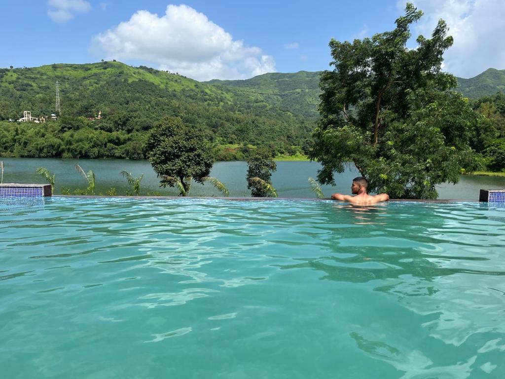 un homme dans une piscine d'une rivière dans l'établissement VRISA Mountain Retreat, à Pune