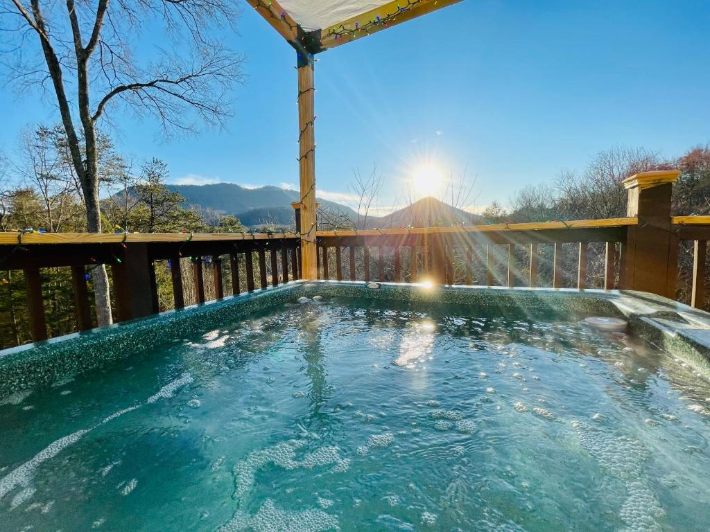 a hot tub on a deck with the sun in the background at Bear Doodle 2.0 in Sevierville