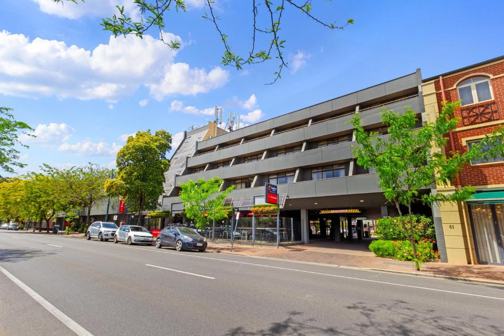 a street with cars parked in front of a building at Econo Lodge North Adelaide in Adelaide