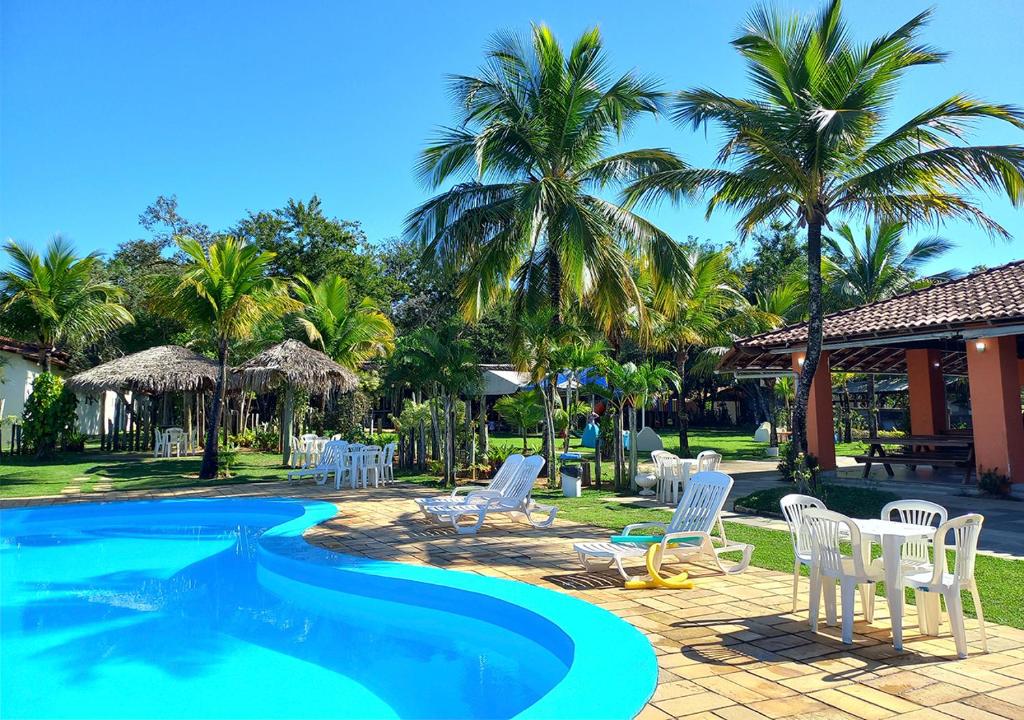 a resort with a swimming pool with white chairs and palm trees at Acquamarine Park Hotel in Guarapari