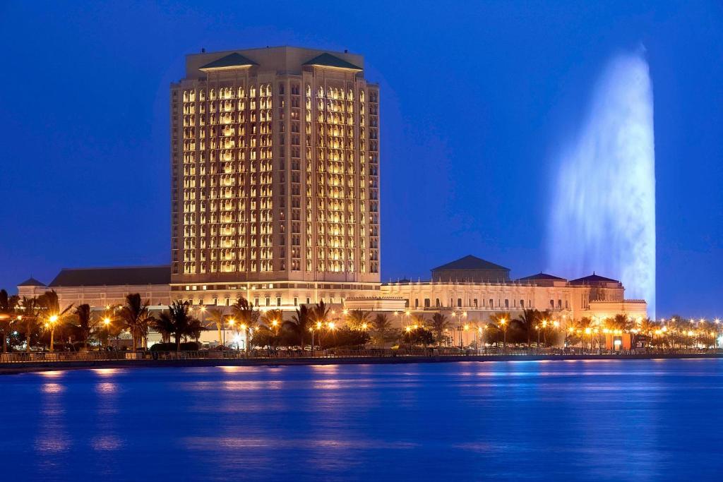 ein großes Gebäude neben einem Wasserkörper in der Nacht in der Unterkunft The Ritz-Carlton Jeddah in Dschidda