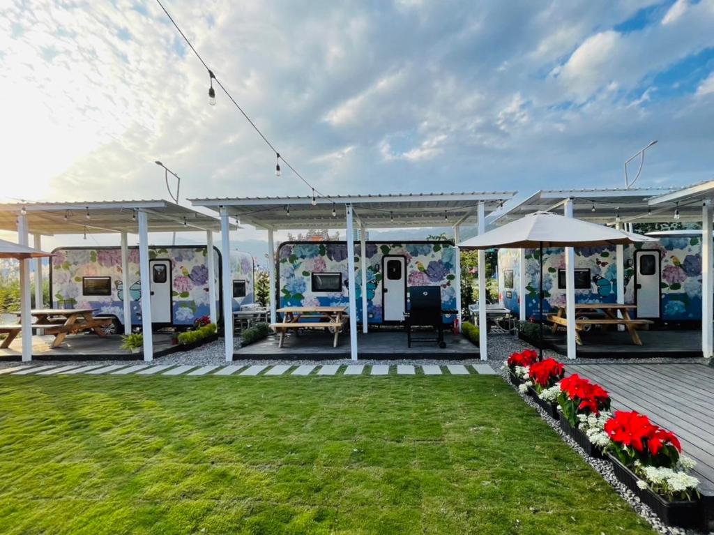 eine Terrasse mit Tischen und Sonnenschirmen im Hof in der Unterkunft 水旅居露營車 in Toucheng