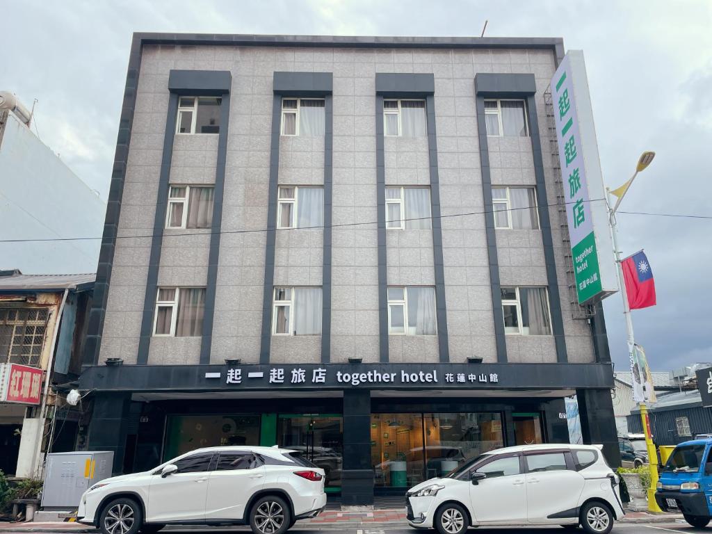 together hotel-Hualien Zhongshan في مدينة هوالين: سيارتين بيض متوقفتين امام مبنى