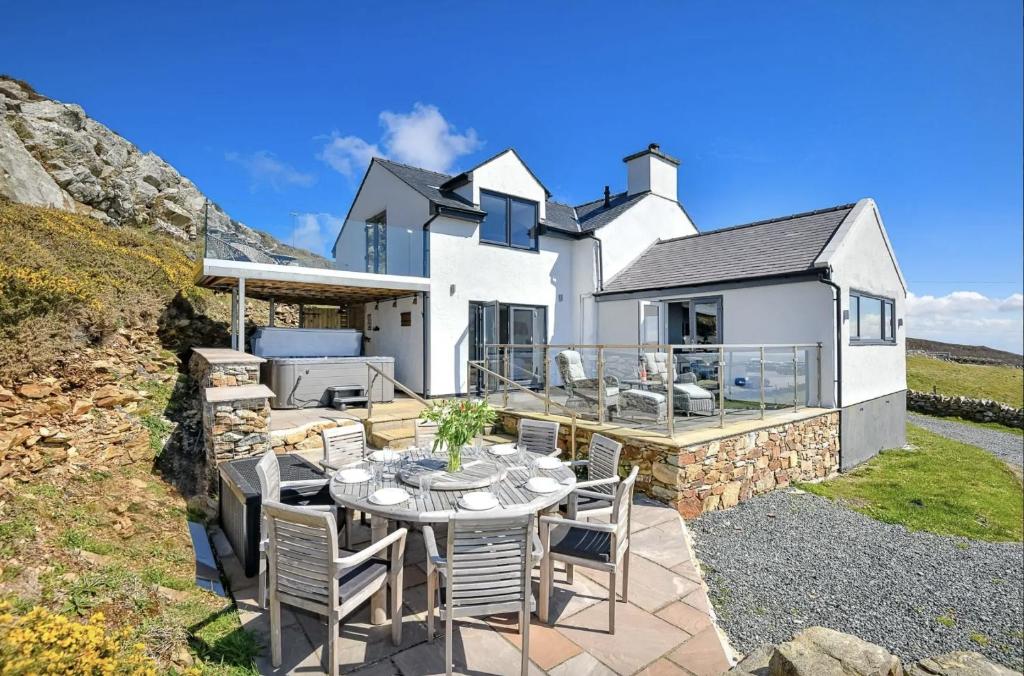 Biały dom ze stołem i krzesłami na patio w obiekcie Goferydd, South Stack, Anglesey, 4 bed luxury home, hot tub, dog friendly w mieście Holyhead