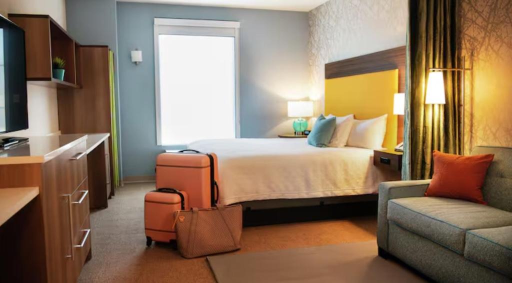 een hotelkamer met een bed, een stoel en een bank bij Home2 Suites By Hilton Dallas East in Dallas