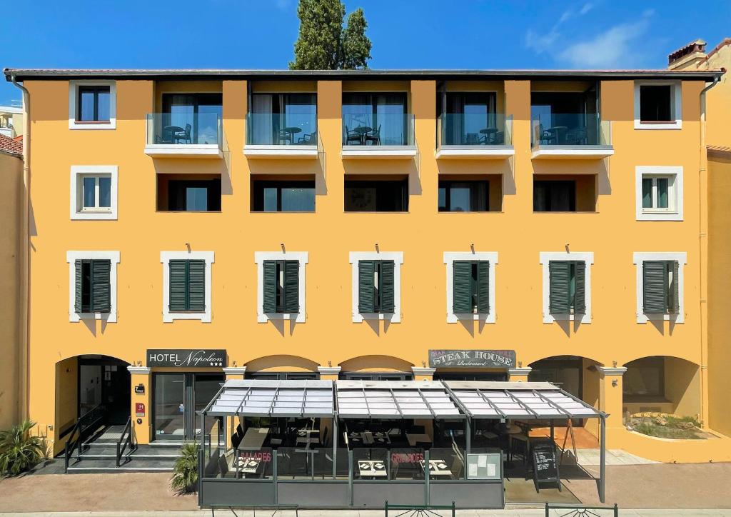 un edificio amarillo con un restaurante delante de él en Hôtel Napoléon, en La Turbie