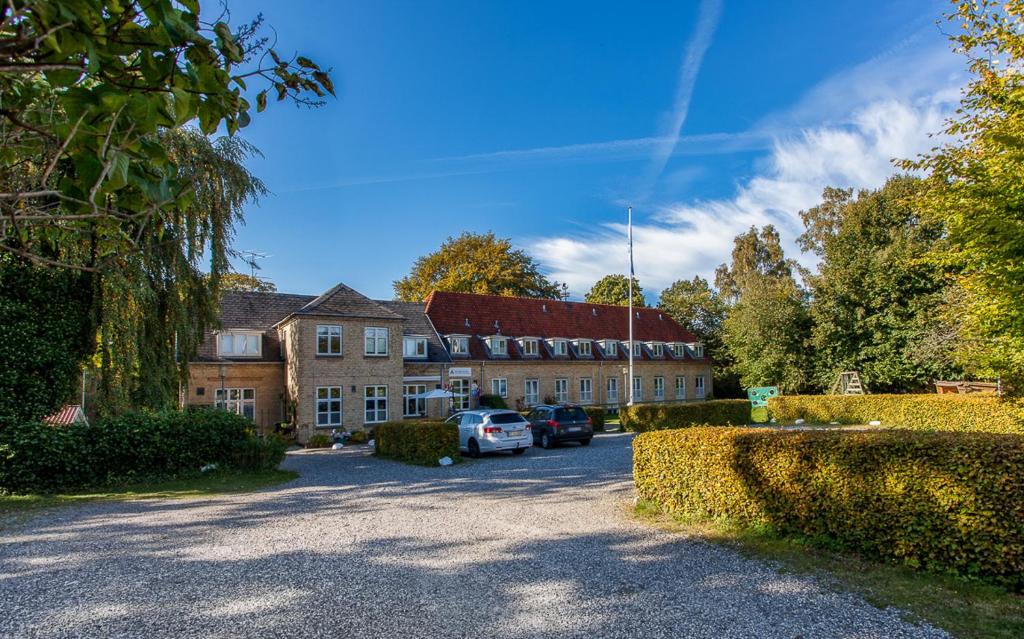 ein großes Gebäude mit Autos in der Einfahrt in der Unterkunft Fredensborg Vandrerhjem, i Kongens baghave in Fredensborg