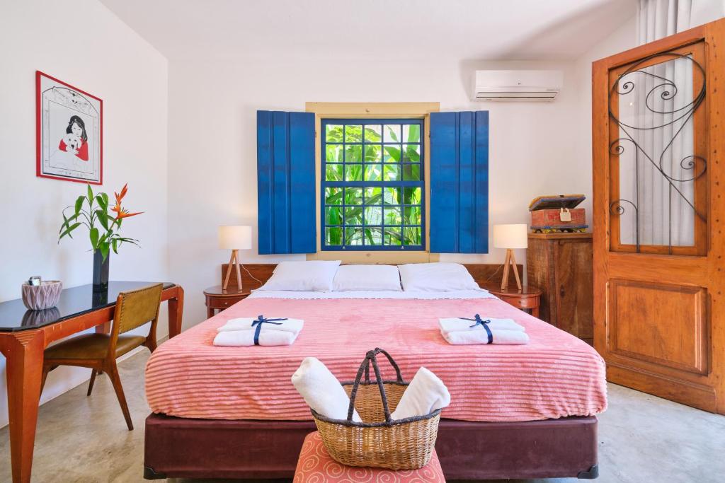 1 dormitorio con cama, escritorio y ventana en Pousada Pontal Gardens, en Paraty