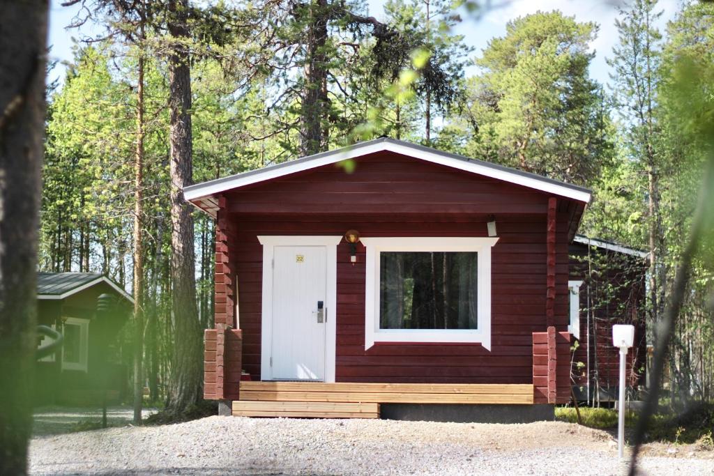 une petite cabine avec une porte blanche dans les bois dans l'établissement Crow Creek Cabins, à Inari