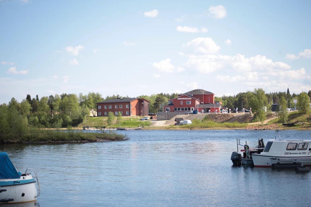 deux bateaux amarrés sur une rivière avec des maisons en arrière-plan dans l'établissement Hotel Inari, à Inari