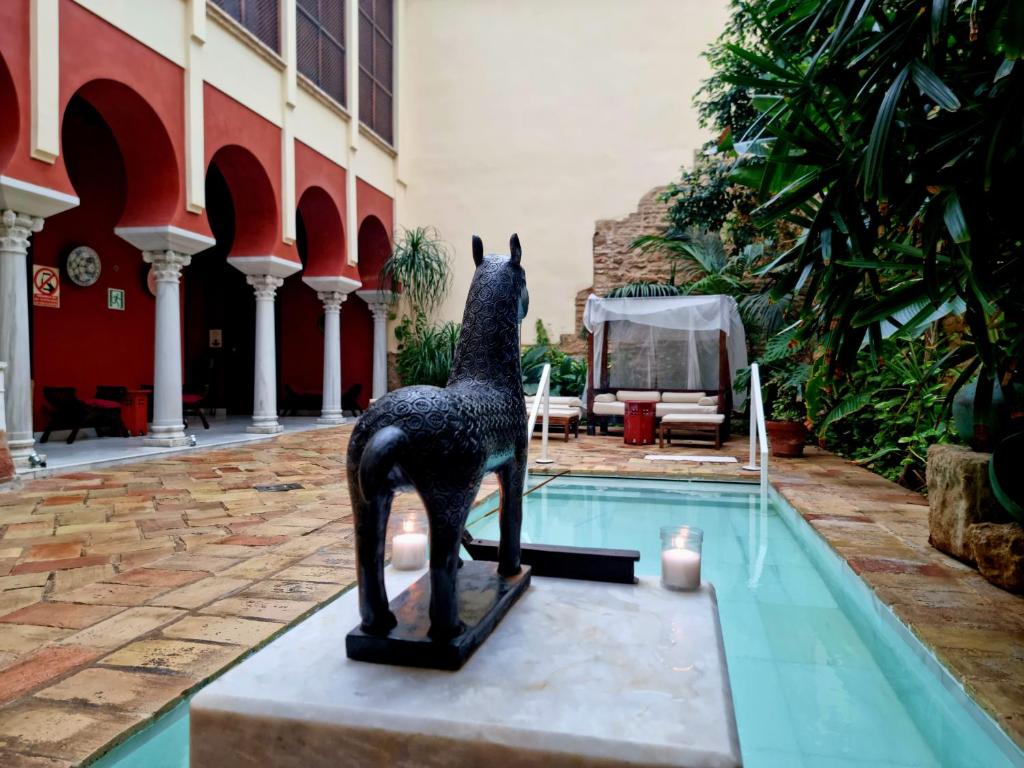 una estatua de una jirafa parada junto a una piscina en Hospedería Baños Arabes de Córdoba Dos, en Córdoba