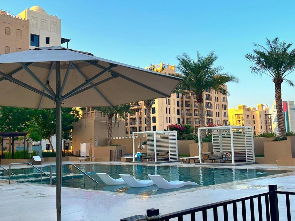 ein großer Pool mit Stühlen und einem Sonnenschirm in der Unterkunft Luxurious Garden View Apartment with Pool & Gym in Madinat Jumeirah in Dubai