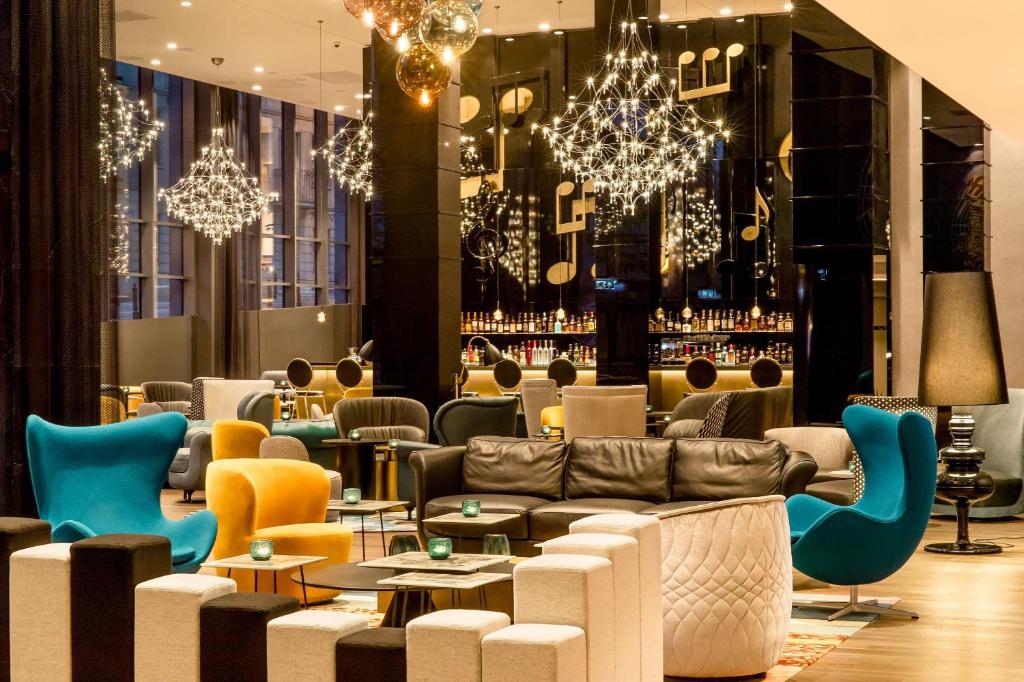 een lobby met banken, tafels en kroonluchters bij Motel One Warsaw-Chopin in Warschau