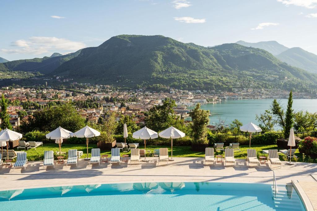 - une piscine avec des chaises et des parasols et une vue sur la ville dans l'établissement A-ROSA Gardasee, à Salò