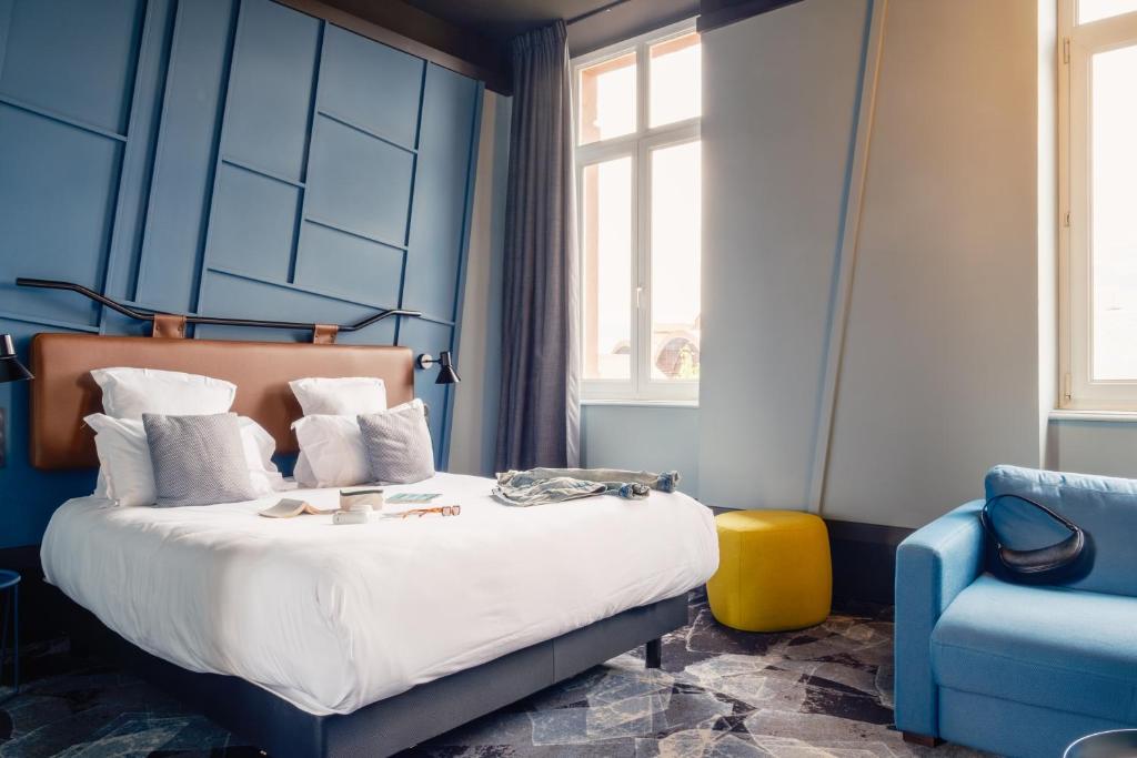 a blue bedroom with a bed and a blue chair at Hôtel Tandem - Boutique Hôtel in Strasbourg