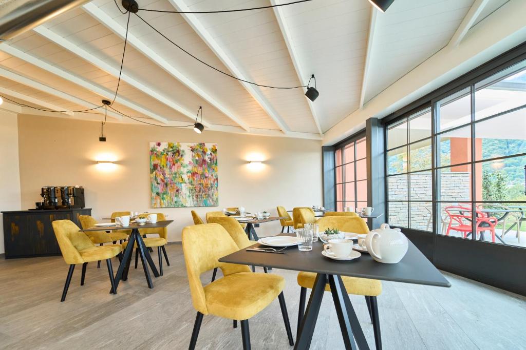 a dining room with tables and chairs and windows at Hotel Villa Cuserina in Cannobio