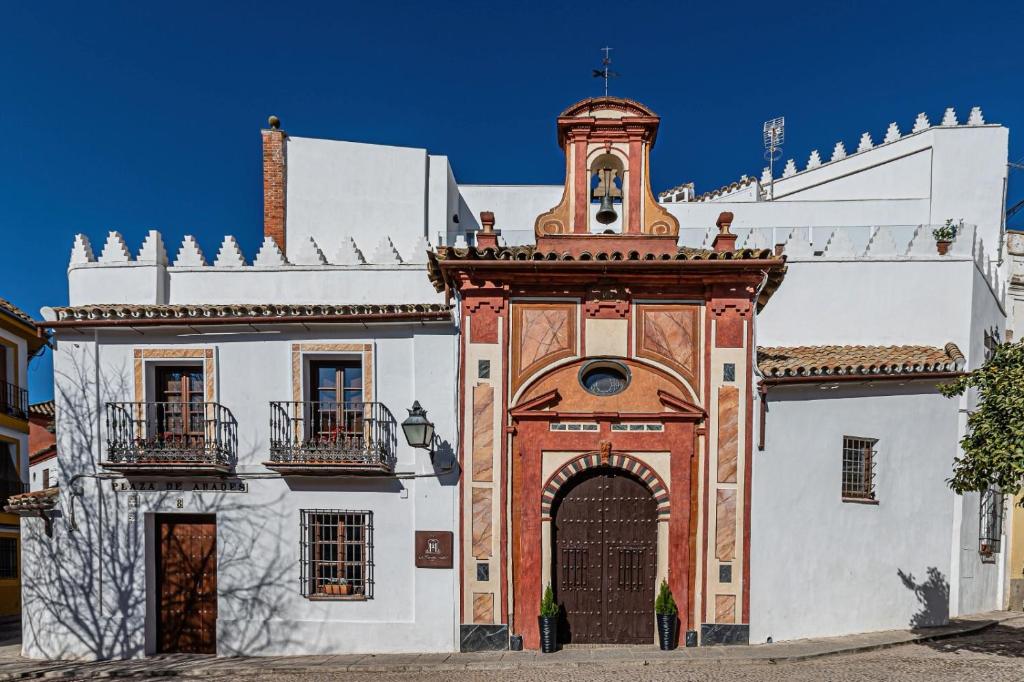 a building with a gate and a clock tower at La Ermita Suites - Único Hotel Monumento de Córdoba in Córdoba