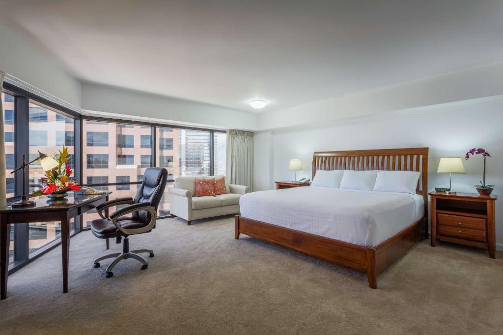 a hotel room with a bed and a desk and a chair at Aston at the Executive Centre Hotel in Honolulu