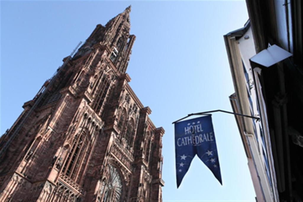 a clock tower with a flag in front of a building at Hotel Cathédrale in Strasbourg