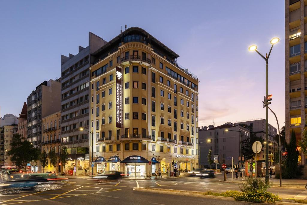 un edificio alto en una calle de la ciudad con coches en America Diamonds Hotel, en Lisboa