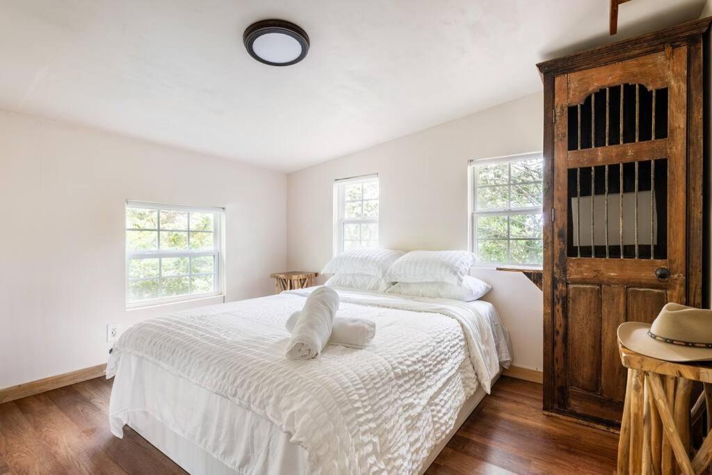 a bedroom with two beds with white sheets and windows at Cozy Coop Casita - Lake Travis-Hot Tub-Tiny House in Austin