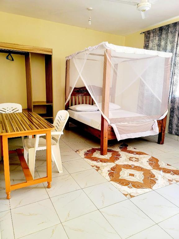 - une chambre avec un lit, une table et des chaises dans l'établissement Casuarina Lounge, à Malindi