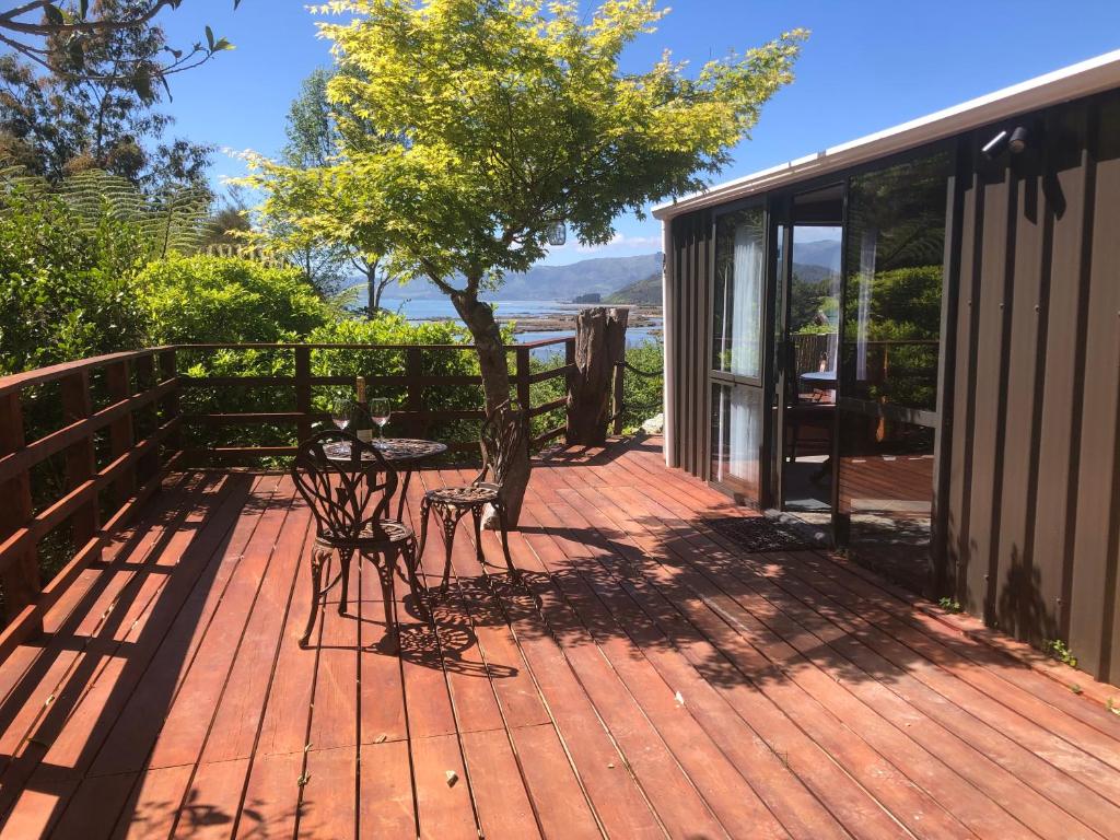 una terrazza in legno con tavolo e sedie. di Heron Hideaway at First Light Rangihaeata Retreat a Rangihaeata