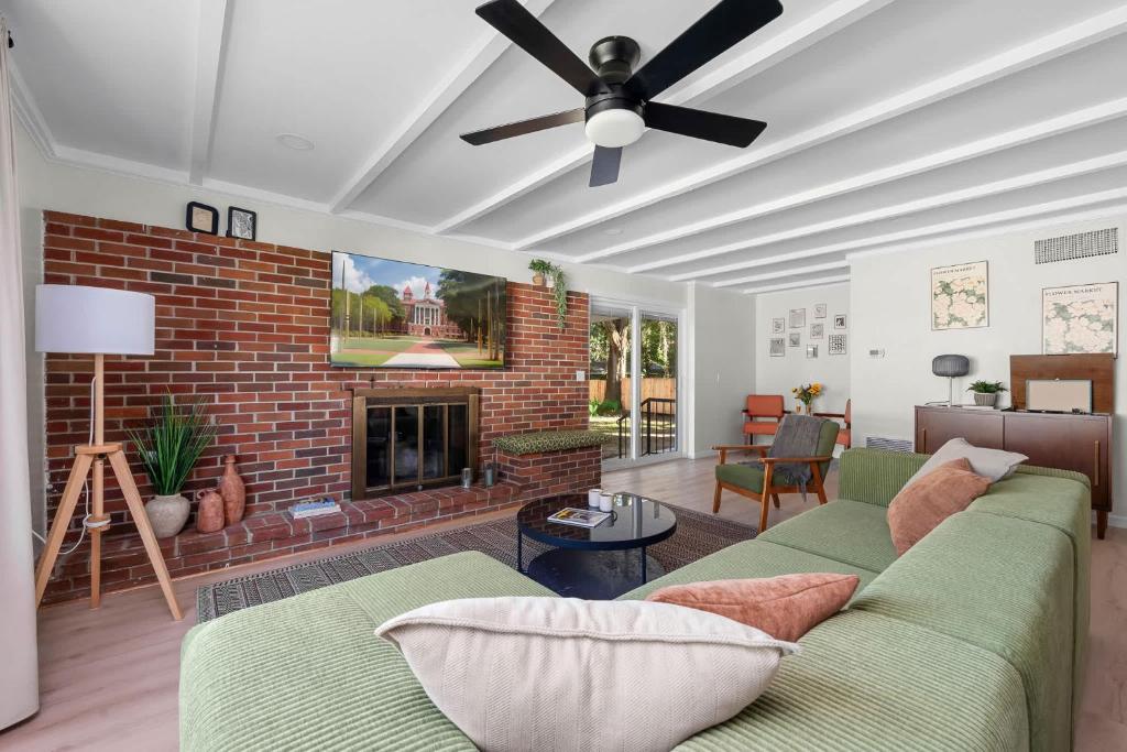 a living room with a couch and a brick fireplace at Retro Revival - Mid-Century Refuge with a '70s Twist in Alachua