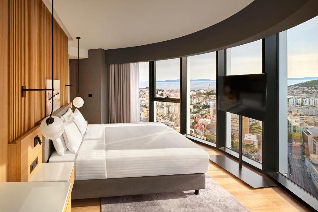 um quarto com uma cama branca e janelas grandes em AC Hotel by Marriott Split em Split