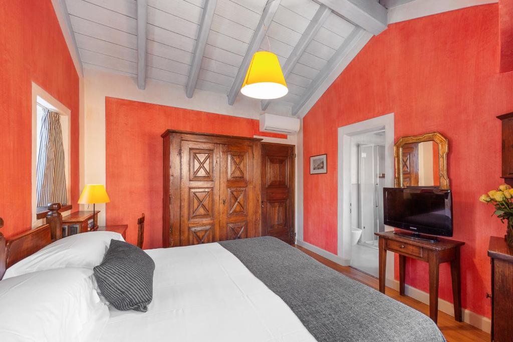 a bedroom with red walls and a bed and a television at Hotel Pironi in Cannobio