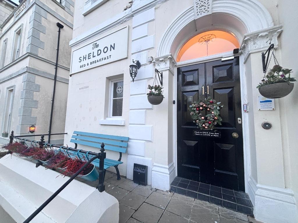 a building with a blue bench in front of a door at The Sheldon B&B - FREE private parking in Eastbourne