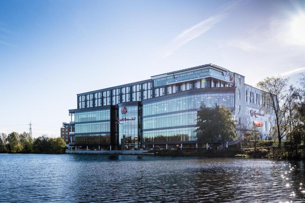 een groot glazen gebouw naast een waterlichaam bij Genting Hotel & Spa at Resorts World Birmingham in Bickenhill