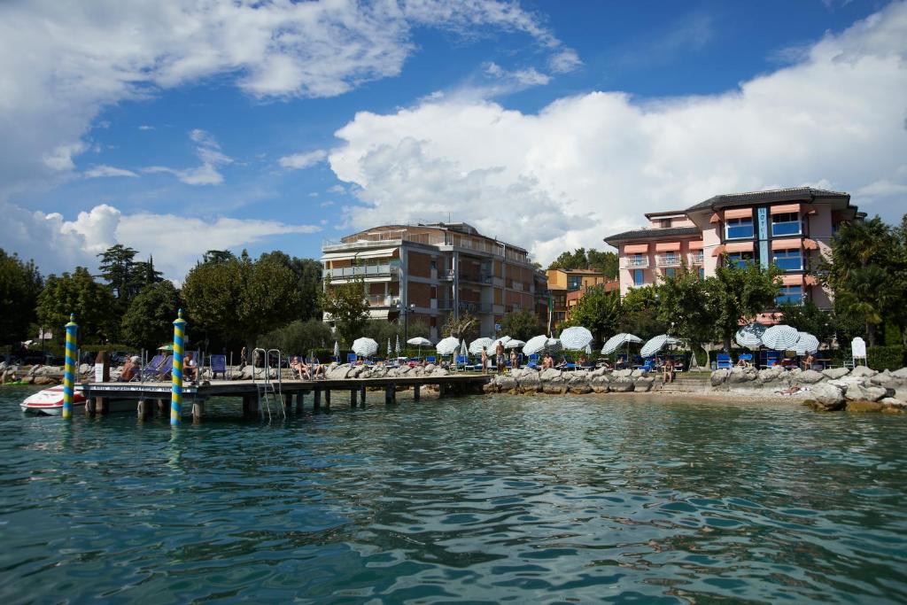 een steiger met stoelen en parasols op een strand bij Front Lake Apartment Bardolino in Bardolino