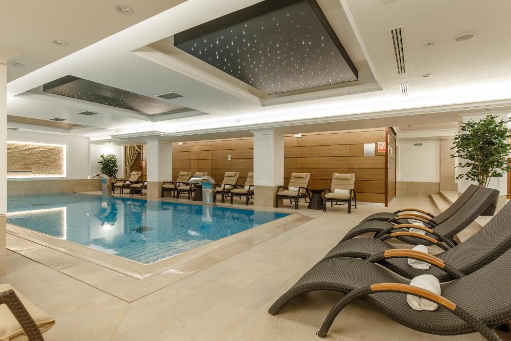 a pool in a hotel room with chairs and tables at Hotel Gabriela in Vişeu de Sus