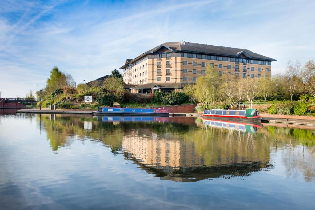 een groot gebouw naast een rivier met boten erin bij Copthorne Hotel Merry Hill Dudley in Dudley