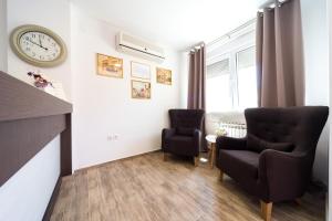 a living room with two chairs and a clock on the wall at Villa Gradski Vrt in Osijek