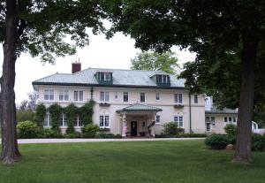 ein großes weißes Haus mit Rasen und Bäumen in der Unterkunft The Belvedere Inn & Restaurant in Saugatuck