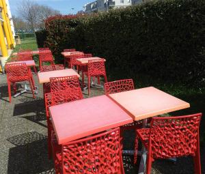 a row of tables and chairs with red metal chairs at Premiere Classe Strasbourg Ouest in Strasbourg