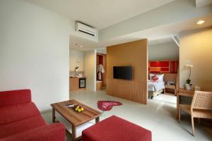 a living room with a red couch and a tv at Kyriad Hotel Airport Jakarta in Tangerang