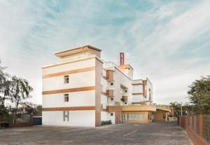 um grande edifício branco num parque de estacionamento em Hotel Dois H em Joinville