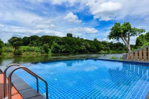 a swimming pool next to a river at Princess River Kwai Hotel in Kanchanaburi City