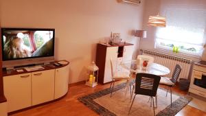 uma sala de estar com televisão e uma mesa com cadeiras em Apartment Dominik em Osijek