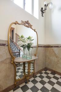 a table with a mirror and a vase with flowers on it at Villa Maria Hotel in Cannobio