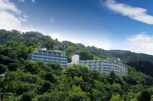 a building on the side of a hill with trees at Wisterian Life Club Usami in Ito